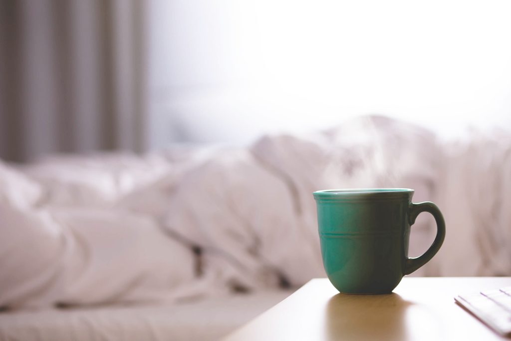 picture of a coffee cup in front of a bed